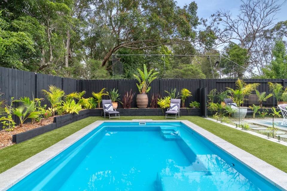 Coral blue fibreglass pool framed by tropical planting in Frankston South